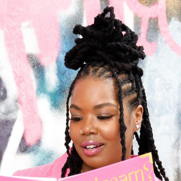 Person holding a pink notebook in front of a colorful graffiti wall