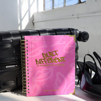 Black suitcase with a pink notebook titled 'Blunt Aftercut' and black high heels on a white floor.